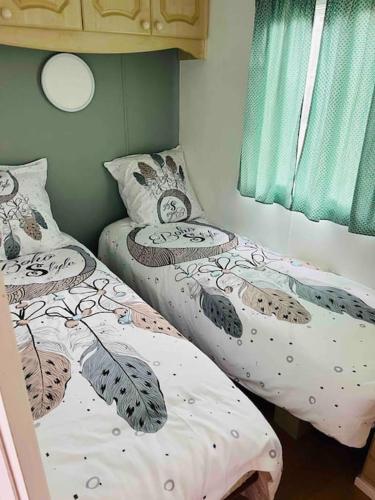 two twin beds in a room with green curtains at Equi-lodge vert au coeur des chevaux & de la nature proche Disney avec possibilité de balade poneys in La Houssaye-en-Brie