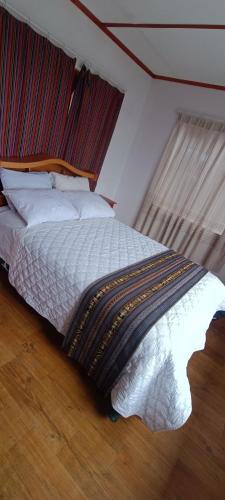 Taquile Lodge Inn في Huillanopampa: غرفة نوم مع سرير مع اللوح الأمامي الخشبي