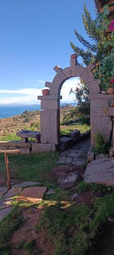 Huillanopampa的住宿－Taquile Lodge Inn，石拱门,在田野上设有长凳