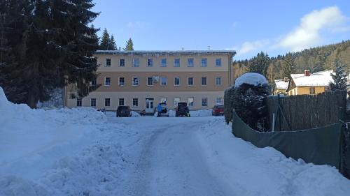 a street covered in snow with a building in the background at Útulný byt v Jizerských horách -Apartmán Mili in Kořenov
