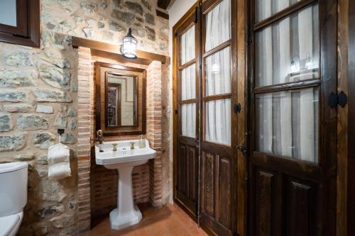 Baño de piedra con lavabo y espejo en Casa del Agüelo, en Cella