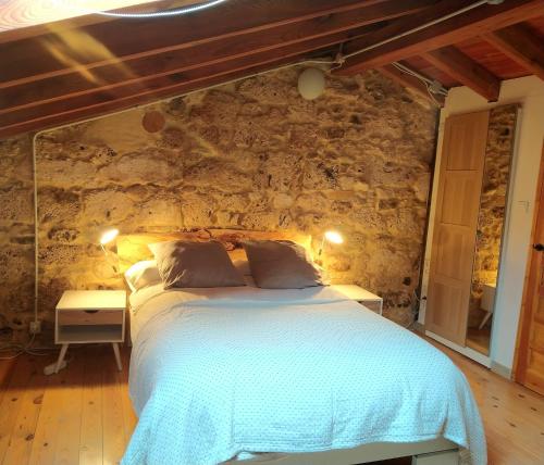 1 dormitorio con cama y pared de piedra en La Milana, Orbaneja del Castillo en Orbaneja del Castillo
