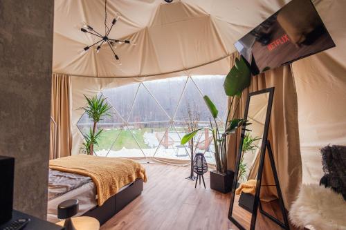 - une chambre avec un lit dans une tente ornée de plantes dans l'établissement Domki i Glamping Nałęczów - Pod Łysą Górą, à Nałęczów