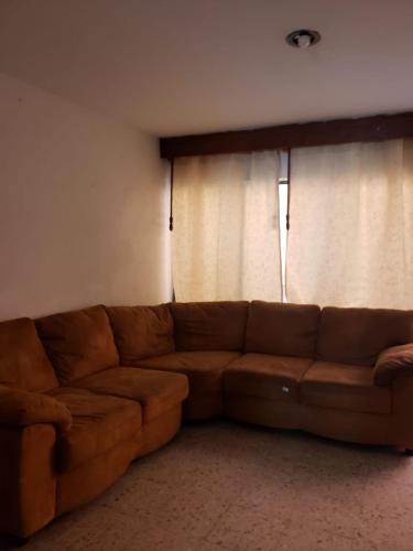 Tu habitación perfecta, está aquí. في مدينة ميكسيكو: أريكة بنية في غرفة المعيشة مع ستارة