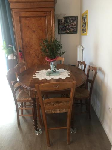 a dining room table with chairs and a vase on it at Chambres in Trappes