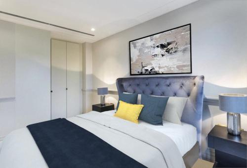 a bedroom with a large bed with a blue headboard at Modern Hammersmith Bridge Flat in London