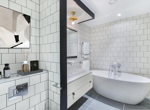 La salle de bains blanche est pourvue d'une baignoire et d'un lavabo. dans l'établissement Modern Hammersmith Bridge Flat, à Londres