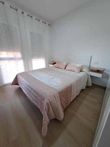 - une chambre blanche avec un grand lit et des oreillers roses dans l'établissement Apartamento Elena, à Fuengirola