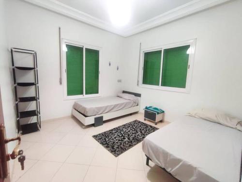 a white room with two beds and two windows at SkyRise Khemisset 2 : 2 bedrooms in Khemisset