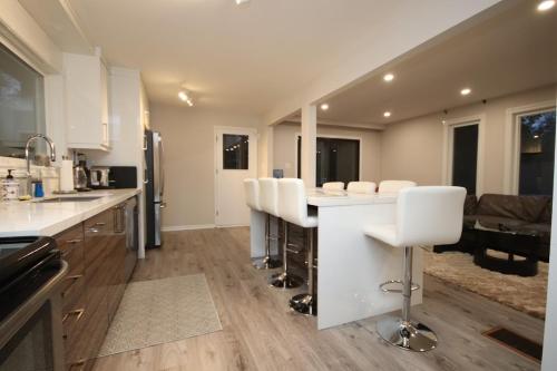 a kitchen with white counter tops and white chairs at La Datcha 20 Acres Private Spa, with Pool, Jacuzzi & Wood Burning Sauna in Cookstown