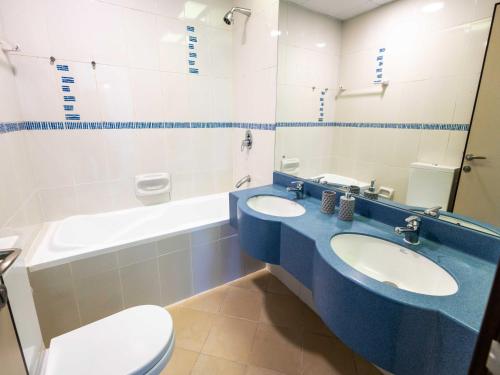 a bathroom with two sinks and a toilet and a tub at Avantha By Afi luxury 2BHK apartment in Dubai