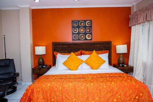 a bedroom with a large bed with an orange wall at Aparthotel Guijarros in Tegucigalpa