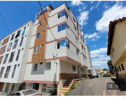 a tall white building with windows on a street at COMODO APARTAMENTO AMOBLADO con piscina fuera del alojamiento a 1 K m in San Gil