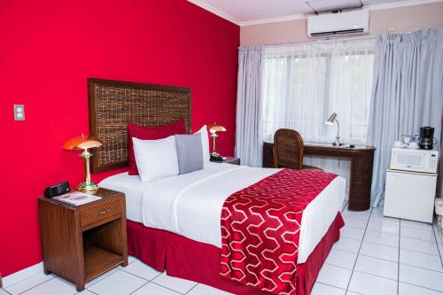 a bedroom with a large bed with red walls at Aparthotel Guijarros in Tegucigalpa