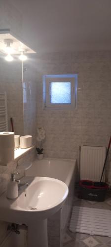 a white bathroom with a sink and a window at Apartament Brasov in Braşov