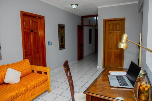 a living room with a couch and a laptop on a table at Aparthotel Guijarros in Tegucigalpa
