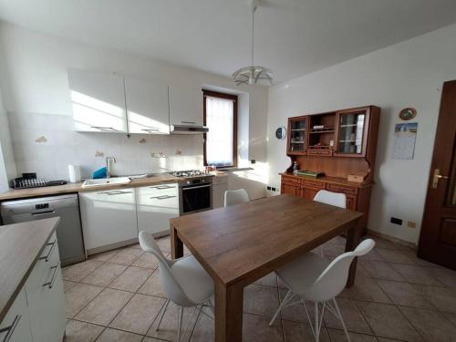 a kitchen with a wooden table and white chairs at Sonia sweet home in Candelo