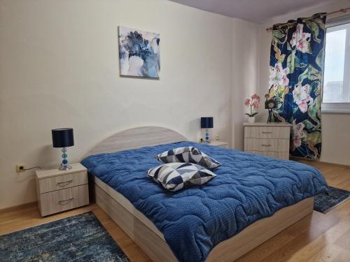 ein Schlafzimmer mit einem Bett mit einer blauen Decke in der Unterkunft Уютен 2-стаен Апартамент в Центъра на Добрич in Dobritsch