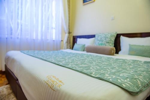 a bedroom with a bed with a green blanket on it at Glamour Suites in Nanyuki