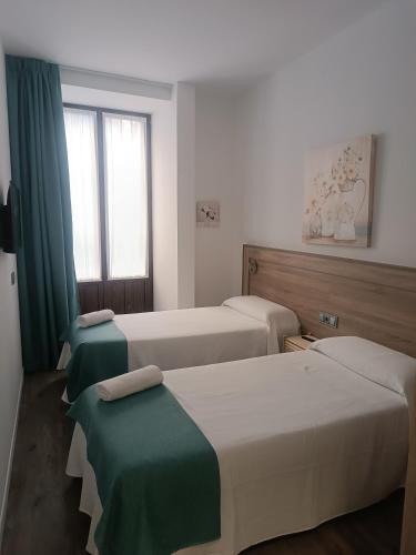 a hotel room with two beds and a window at ApartamentosTuristicos Avila Puerta del Alcazar 0-1 in Ávila