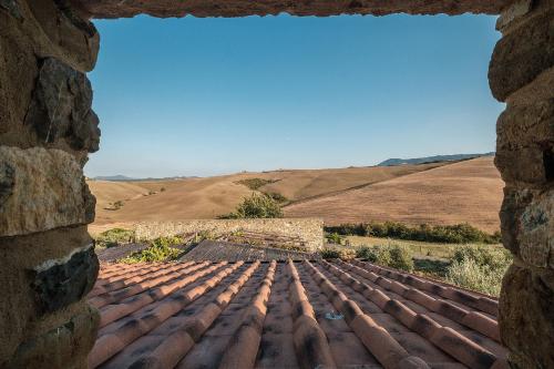 einen Blick aus dem Fenster eines Daches mit Feldern im Hintergrund in der Unterkunft Podere San Pasquale in Castiglione dʼOrcia