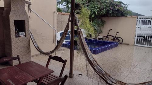 a hammock on a patio with a bike and a table at Santos house casa com dois quartos in Matinhos