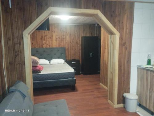 um quarto com uma cama num quarto com paredes de madeira em Cabañas Janico em Loncoche