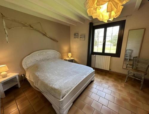une chambre avec un lit, une fenêtre et un lustre dans l'établissement La bergerie des Landes, à Lit-et-Mixe