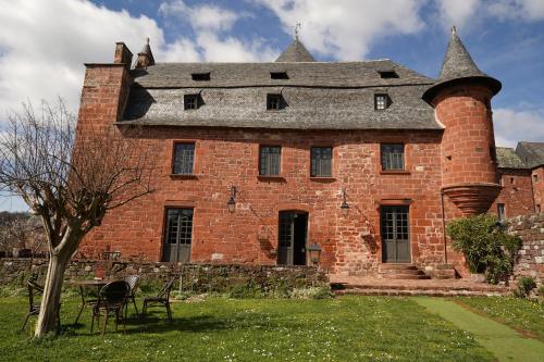 Château de Vassinhac chambres d'hôtes Collonges la rouge في كولونيي: مبنى من الطوب الأحمر قديم مع مدخنة