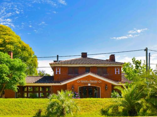 a large red brick house with a roof at Hosteria Del Pescador in Punta Del Diablo