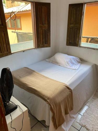 a bed in a room with two windows at Casa de Dandá in Porto Seguro