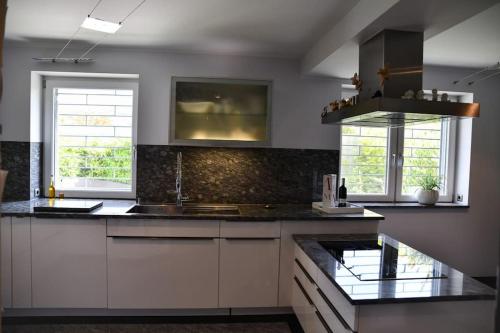 a kitchen with white cabinets and a black counter top at Haus Respirada NRW mit großem Wellnessbereich, Gym in Meckenheim