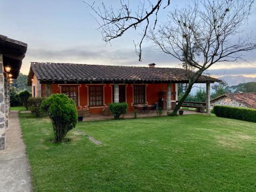 une maison avec une cour verdoyante devant elle dans l'établissement Cabañas Rancho La Laguna, à Zacatlán