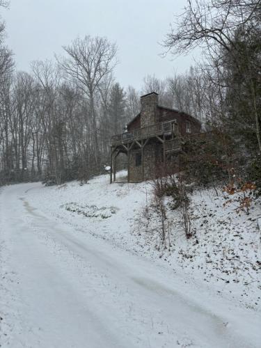 una casa vieja al lado de una carretera cubierta de nieve en Songbird Cabin, en Vilas