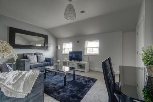 a living room with a couch and a tv at #St Georges Court by DerBnB, Spacious 2 Bedroom Apartments, Free Parking, WI-FI, Netflix & Within Walking Distance Of The City Centre in Derby