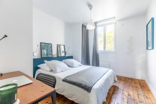 een slaapkamer met een bed en een bureau met een laptop bij La maison de Vallières in Clermont-Ferrand