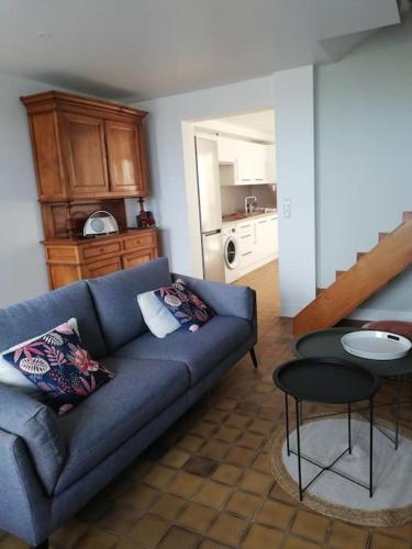 un salon avec un canapé bleu et une cuisine dans l'établissement La Vaillante, à Saint-Valery-sur-Somme