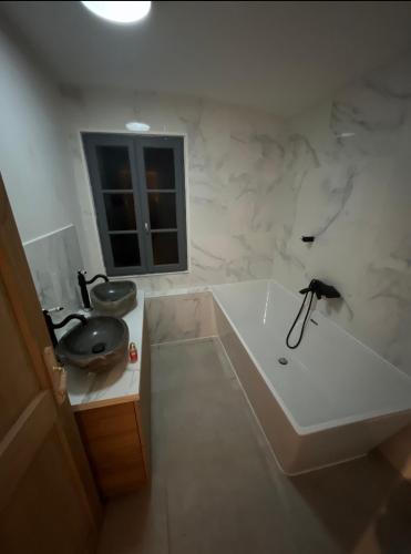 une salle de bain blanche avec une baignoire et un lavabo dans l'établissement La Petite Maison au bord de l’étang, à Chirac