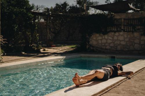 a woman laying on the edge of a swimming pool at Yogam villa Essaouira in Ghazoua