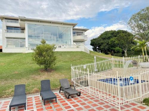 a house with three chairs and a pool in front of it at Lujosa Finca El Ensueño Cerritos Pereira in Pereira