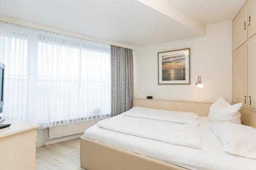 Dormitorio blanco con cama y ventana grande en Ferienwohnung Penthaus Nordmarkhof Sylt Westerland en Westerland