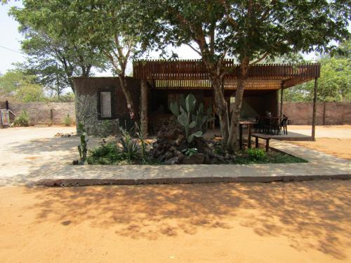 a building with a tree and a table and chairs at POVI Holiday Home in Kasane