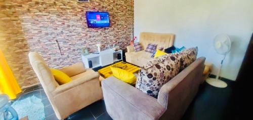 een woonkamer met twee banken en een tv aan een bakstenen muur bij Beautiful and Affordable 1brm in Milimani in Kisumu