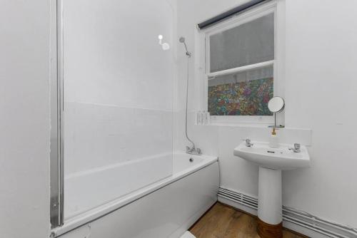 y baño blanco con lavabo y ducha. en Cosy place near Camden town en Londres