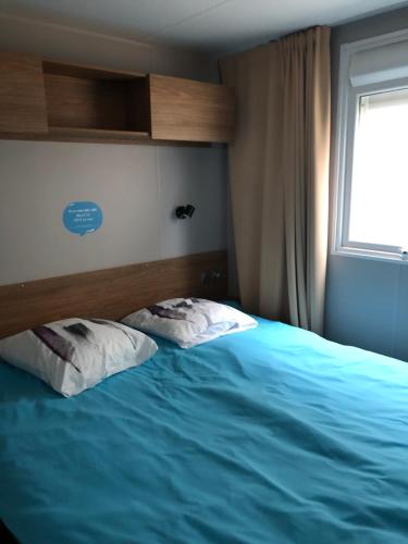a bedroom with two pillows on a bed with a window at Mobilhome 6-8 personnes Clim in Saint-Jean-de-Monts