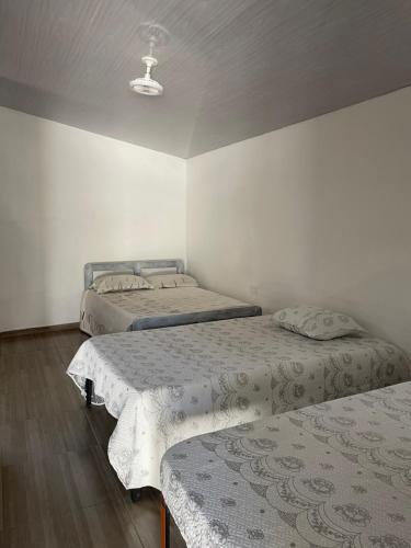 three beds in a room with white walls at Ancestral Casa de Campo in Roldanillo