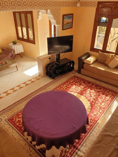 a living room with a purple rug and a tv at Sidibouzid appartement in El Jadida