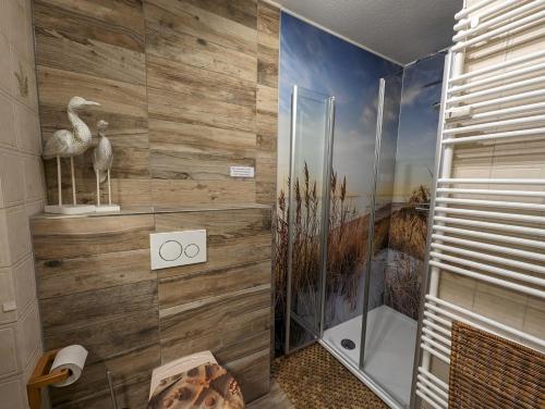 a bathroom with a shower with a wall of wood at Grüne Düne Meerblick in Friedrichskoog-Spitz