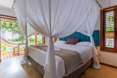 - une chambre avec un lit à baldaquin dans l'établissement Paraíso Casa Branca, à Arraial d'Ajuda
