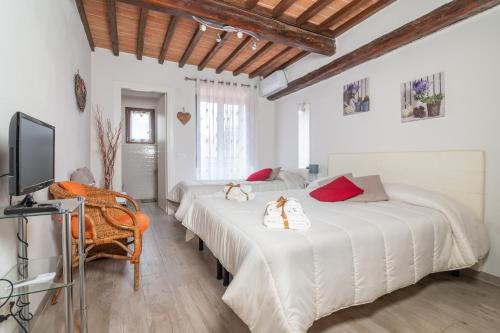 two beds in a white room with a tv at Casa per la Costa in Colle Val D'Elsa